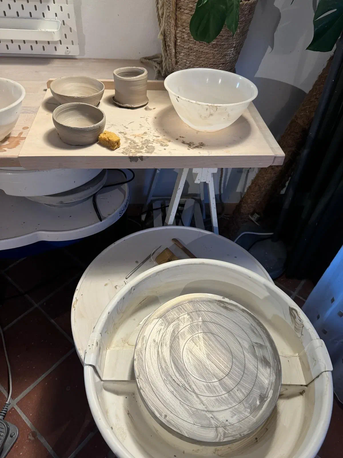 Cuencos y tazas hechos a mano junto a un torno después de la sesión de cerámica de Kevin Cuencos y tazas hechos a mano junto a un torno después de la sesión de cerámica de Kevin
